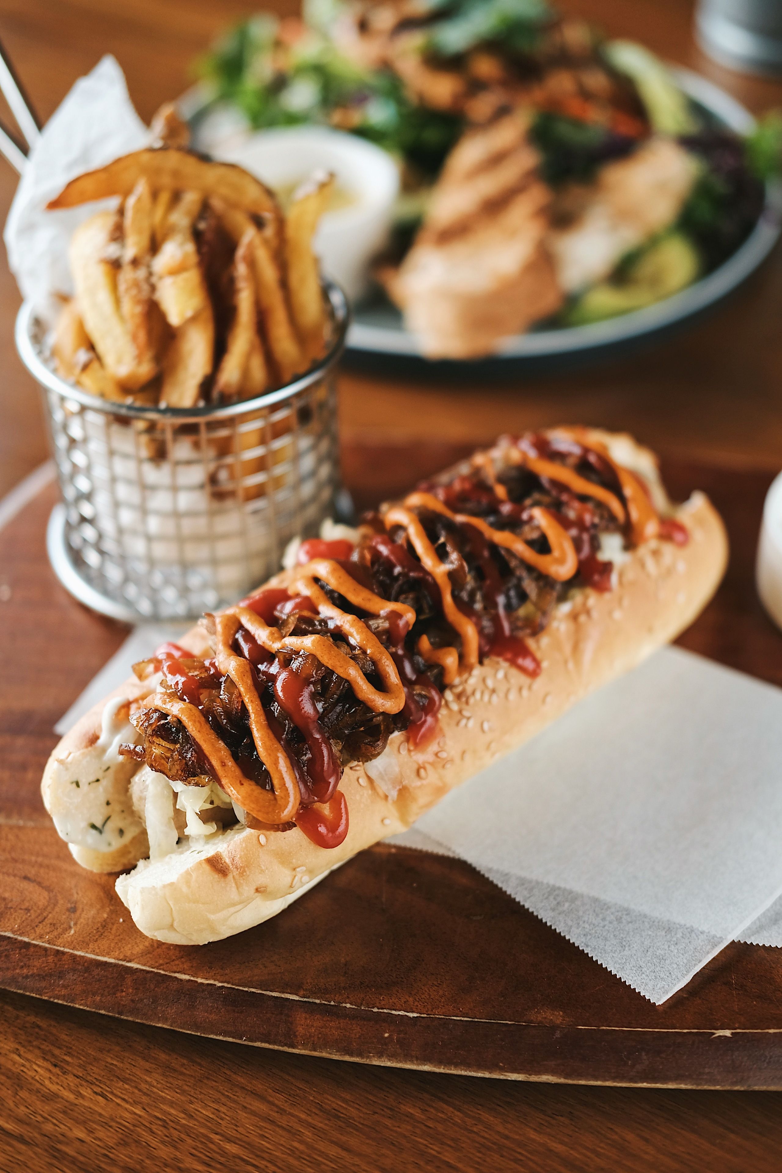 A sandwich with toppings and fries on a wooden table.