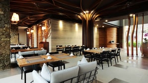 A modern dining area with multiple tables and chairs, stone accents, and contemporary lighting fixtures. - Mahogany Hotel (Nusa Dua)