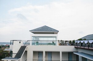A modern building with a glass balcony, a staircase, and a view of the surrounding area.