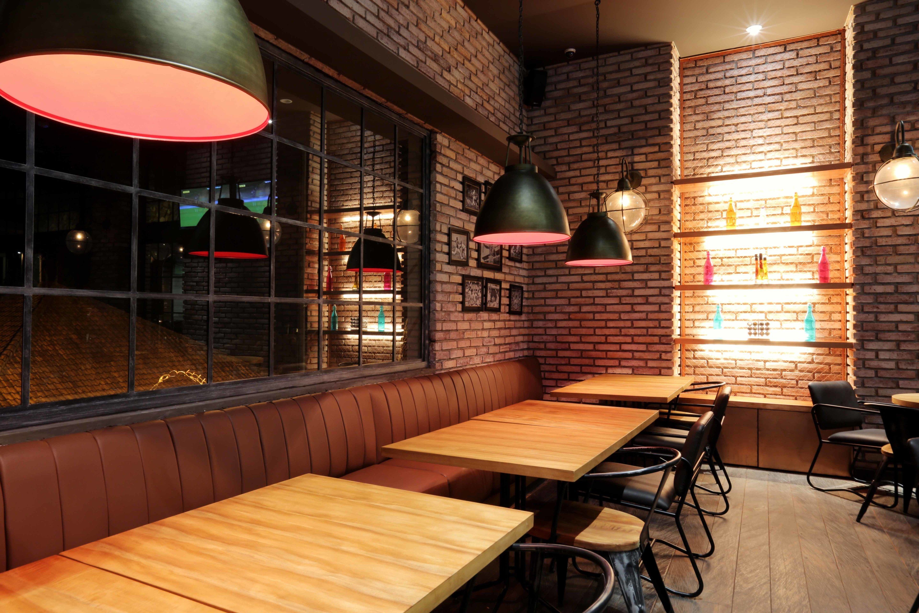 A restaurant interior with brick walls, wooden tables, and leather booths.