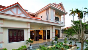 A two-story building with a balcony, potted plants, and a well-maintained garden. - Han Thuyen Homestay (Da Nang)