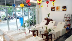 A modern spa with white leather chairs, a glass partition, and red and yellow lanterns. - Han Thuyen Homestay (Da Nang)