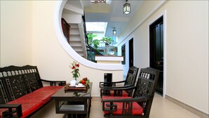 A room with a round mirror, a sofa, a chair, and a small table with a vase of flowers. - Han Thuyen Homestay (Da Nang)