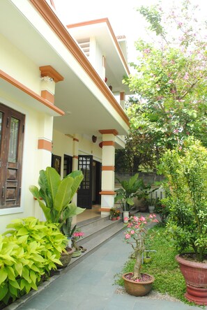 A house with a porch, large potted plants, and a small garden area. - Han Thuyen Homestay (Da Nang)