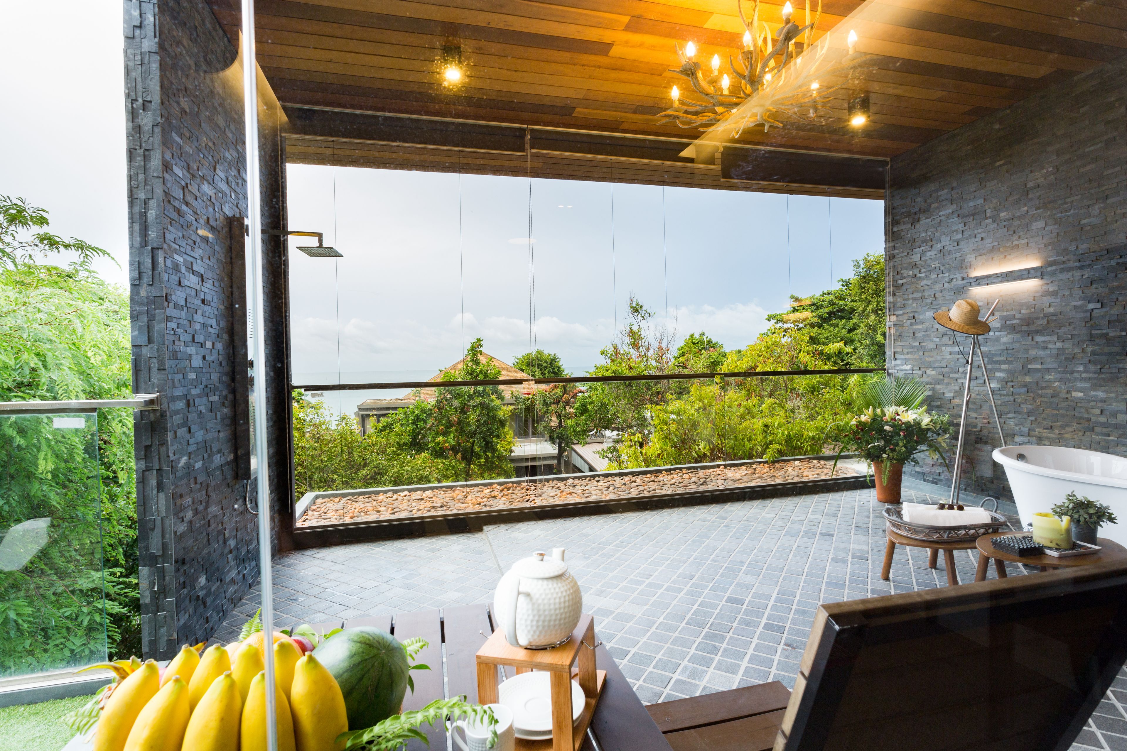 A modern room with a large window, a wooden ceiling, and a view of greenery outside.