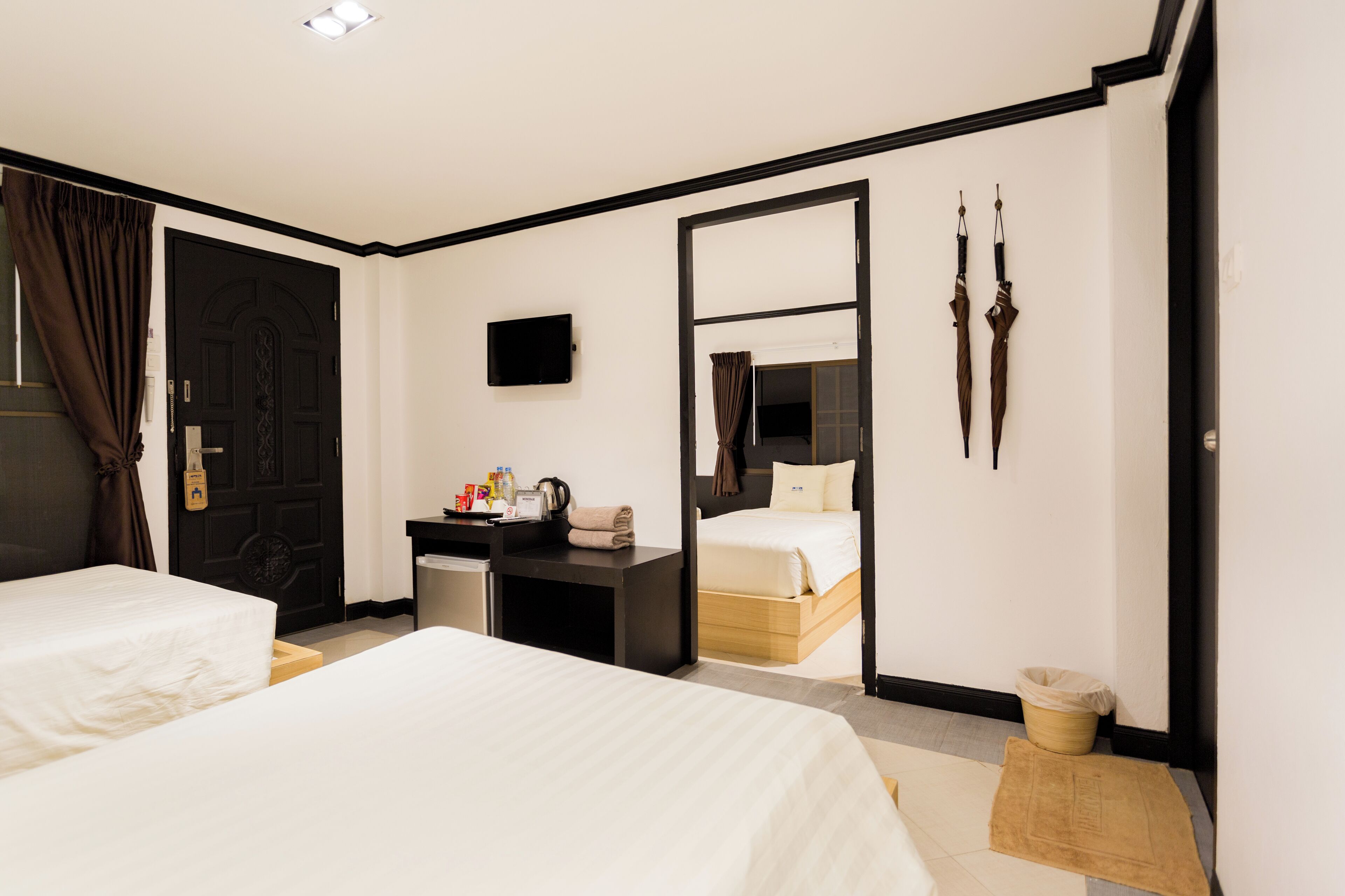 Habitación de hotel con dos camas, un escritorio con televisor, un espejo y un par de esquíes en la pared.