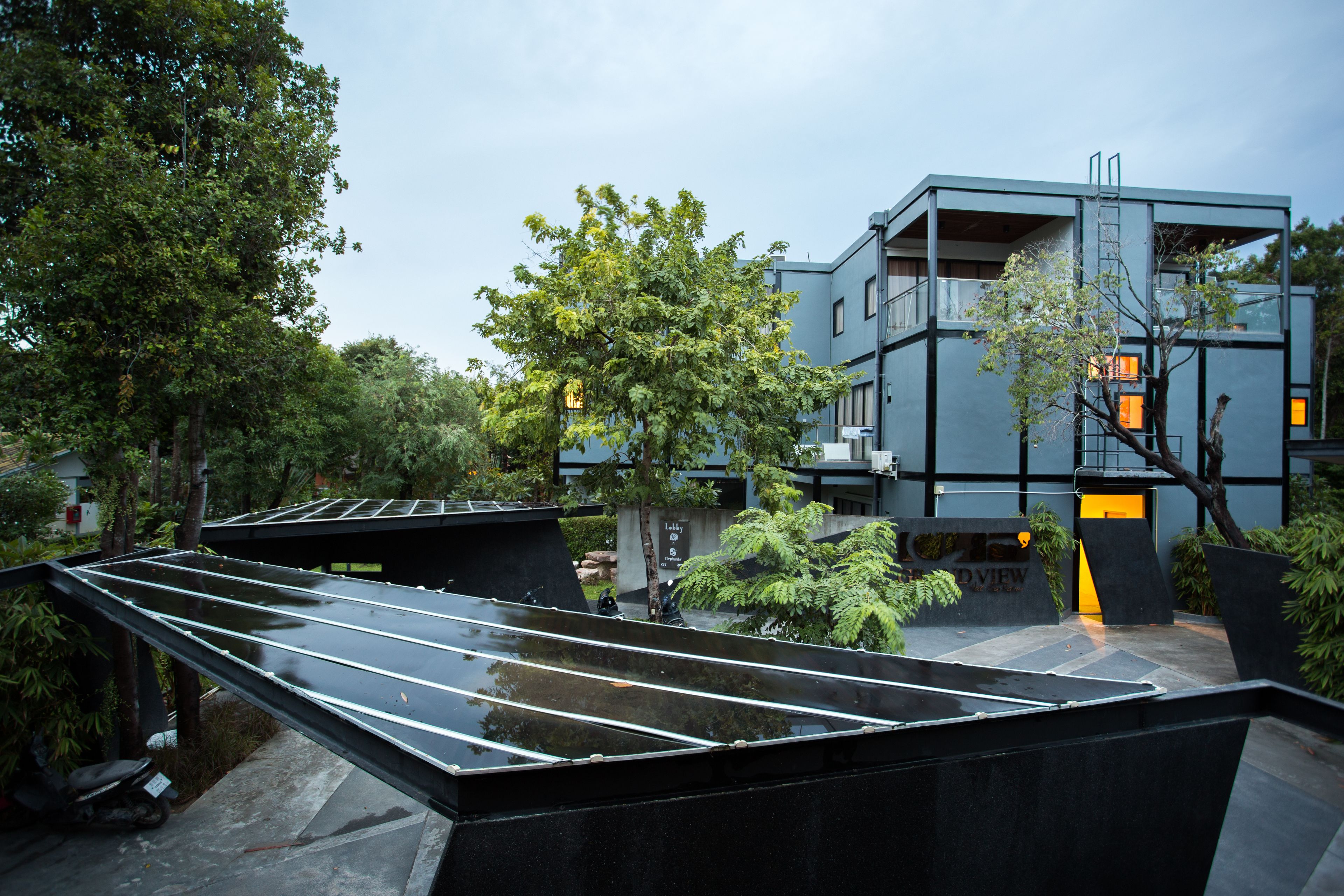 A modern building with a flat roof, surrounded by trees and greenery.