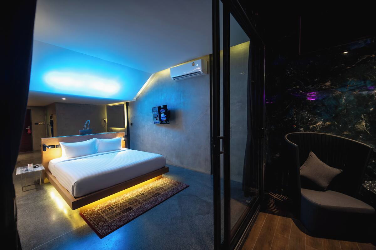 A modern hotel room with a bed, bedside table, and a digital screen on the wall.