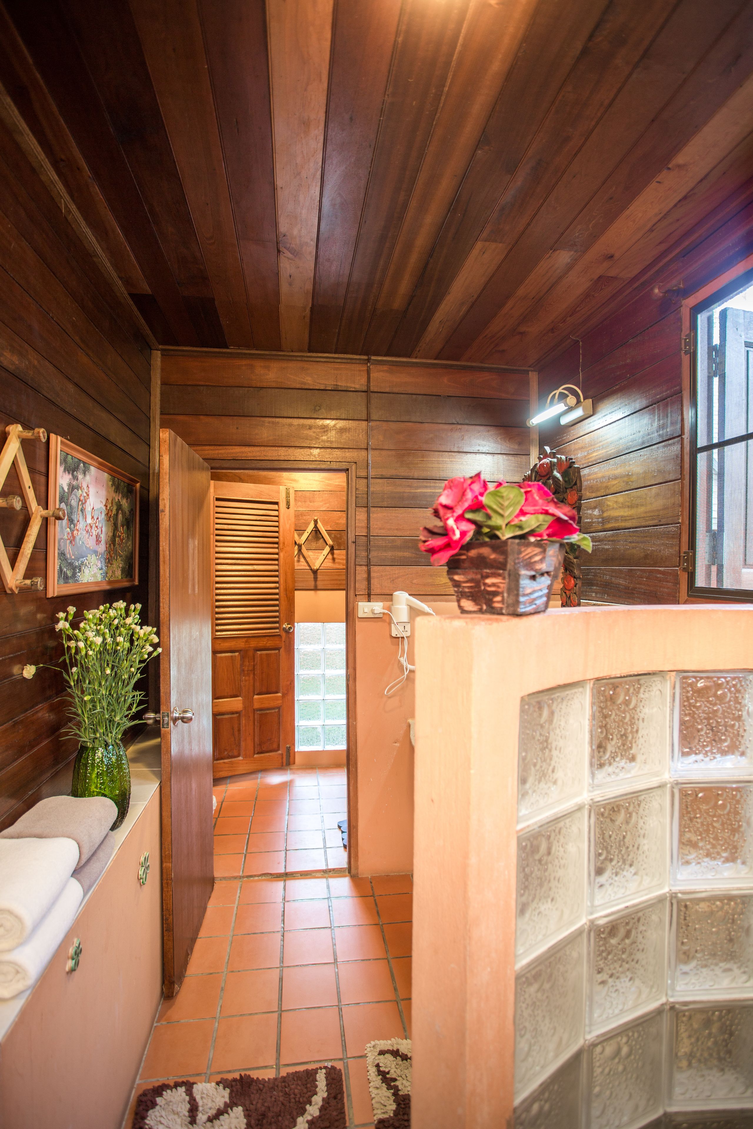 A wooden interior hallway with a tiled floor, a wooden door, and a window.