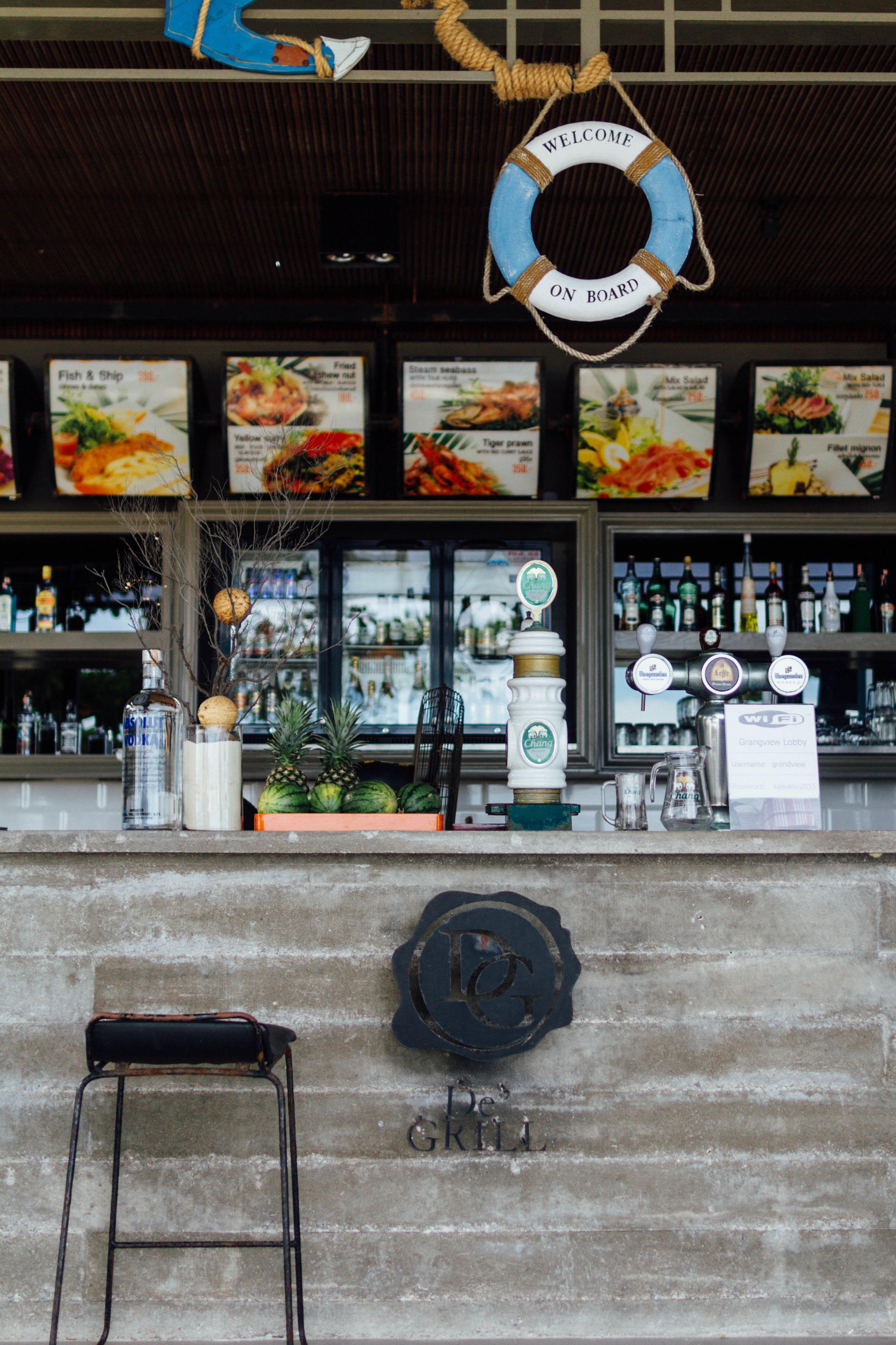 Un espace bar avec un panneau indiquant la présence d’une bouée de sauvetage, un robinet à bière et un tableau affichant le menu.