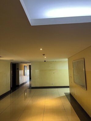 A hallway with a ceiling light, a door, and a wall-mounted screen. - Clubhouse World Hotel Jakarta Bandengan (Jakarta)
