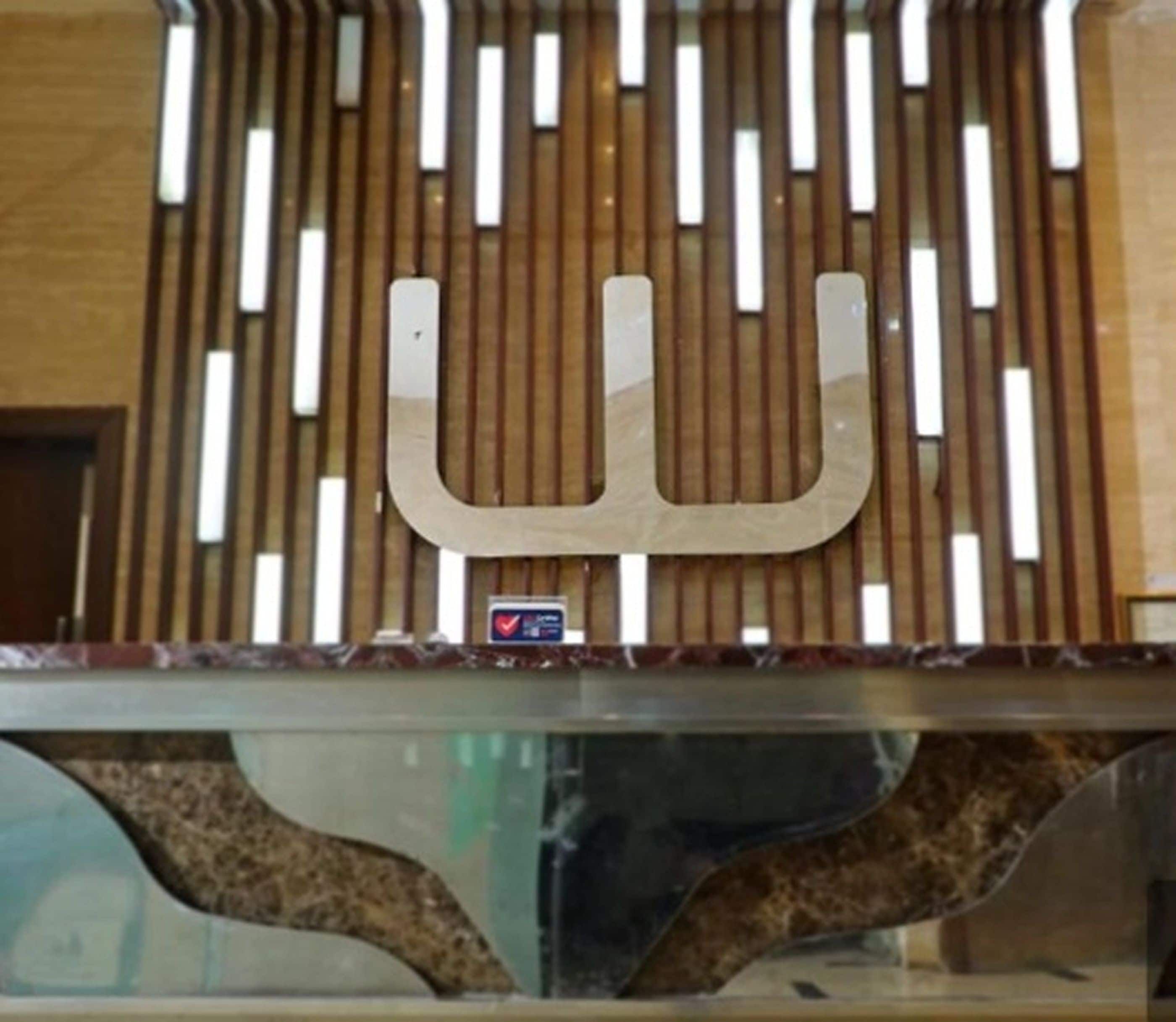 A reception desk with a modern design, featuring a unique letter-shaped logo and a small heart-shaped sign indicating a special offer or feature.