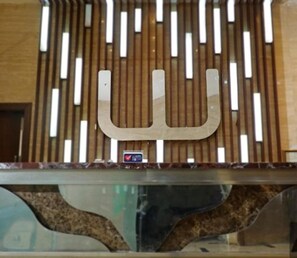 A reception desk with a modern design, featuring a unique letter-shaped logo and a small heart-shaped sign indicating a special offer or feature. - Clubhouse World Hotel Jakarta Bandengan (Jakarta)