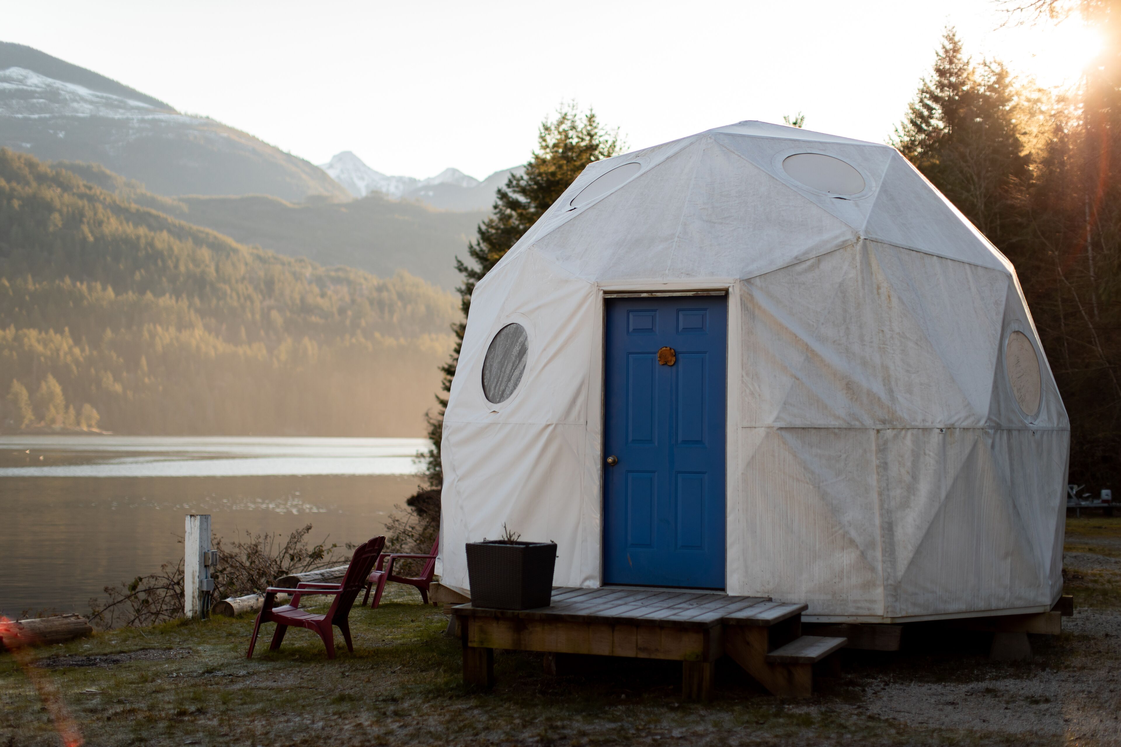 A geodesic dome structure with a blue door, a bench, and a chair outside.