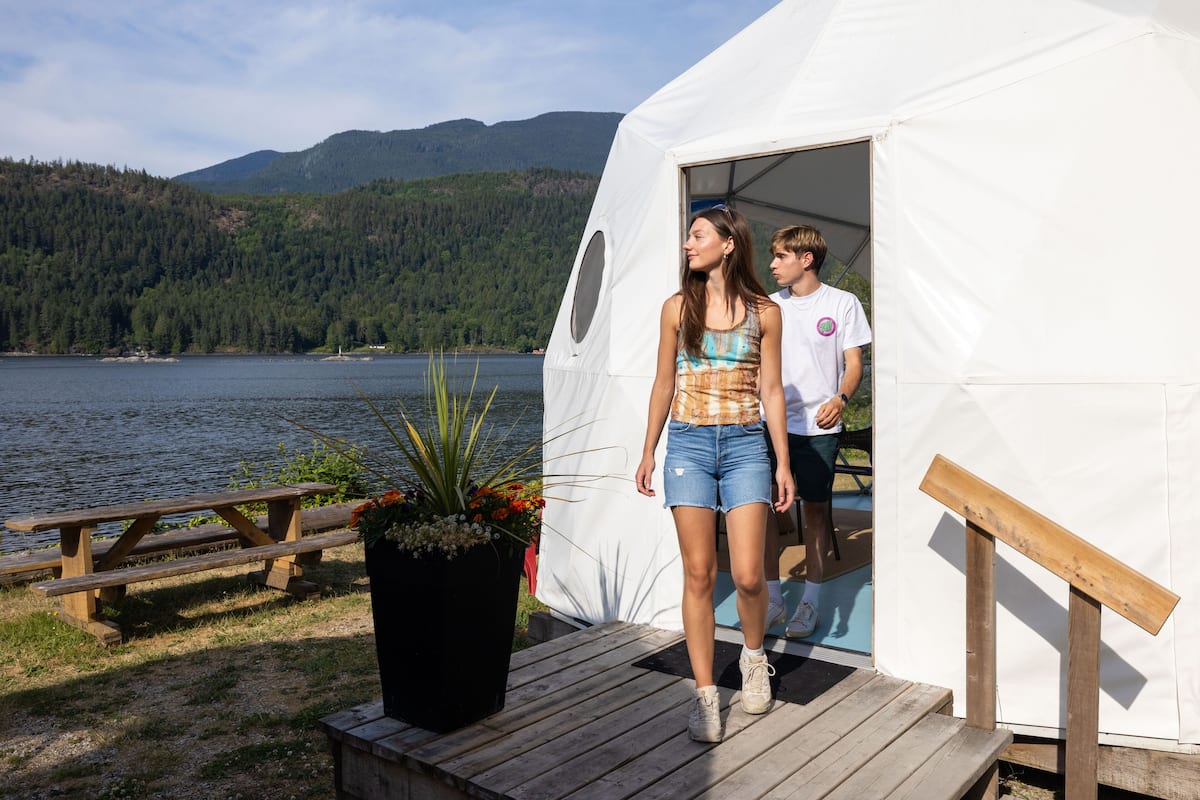 Una tenda amb terrassa de fusta i taula de pícnic al costat d'un llac.
