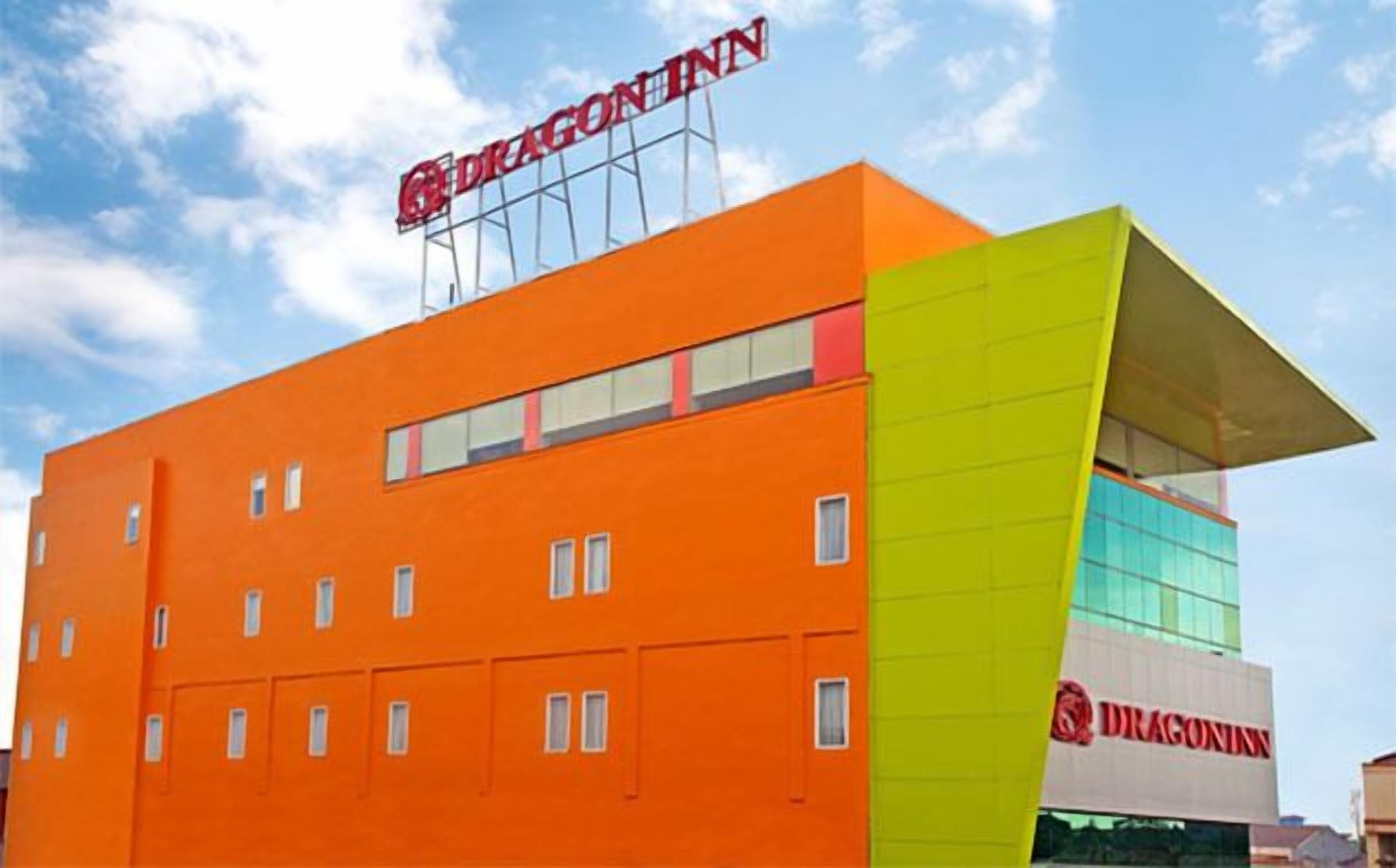 A modern building with a bright orange facade and a green accent. The building has multiple windows and a prominent sign reading "DRAGON INN".