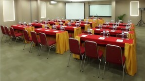 Un salón de conferencias con varias mesas y sillas, equipado con micrófonos y proyectores.