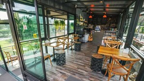 An interior with wooden tables and chairs, large windows, and a bar area. - The Piano Resort (Pak Chong)