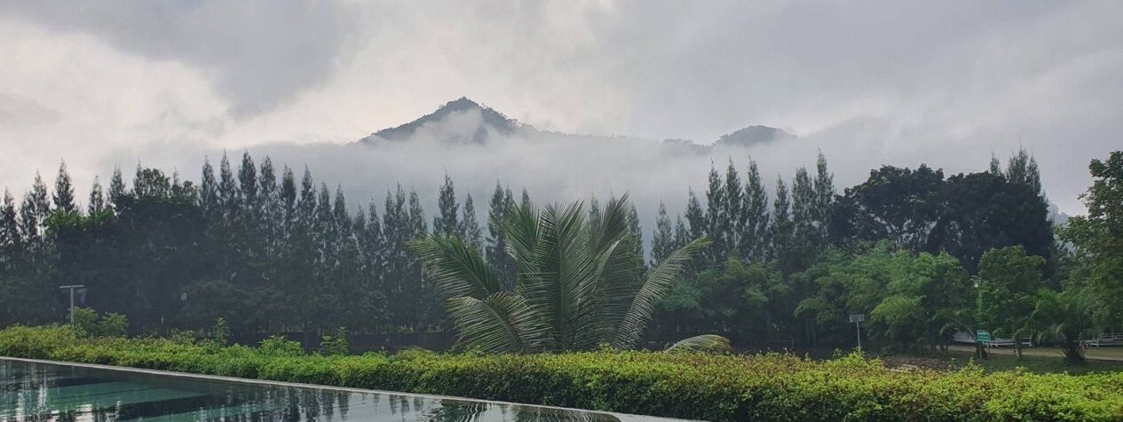 A pool area with a view of a mountain range partially obscured by clouds.