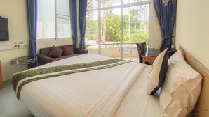 A hotel room with a large bed, a sofa, a dining table, and a TV. - The Piano Resort (Pak Chong)