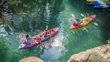Dos kayaks en un río tranquilo con agua cristalina, rodeado de rocas y vegetación.