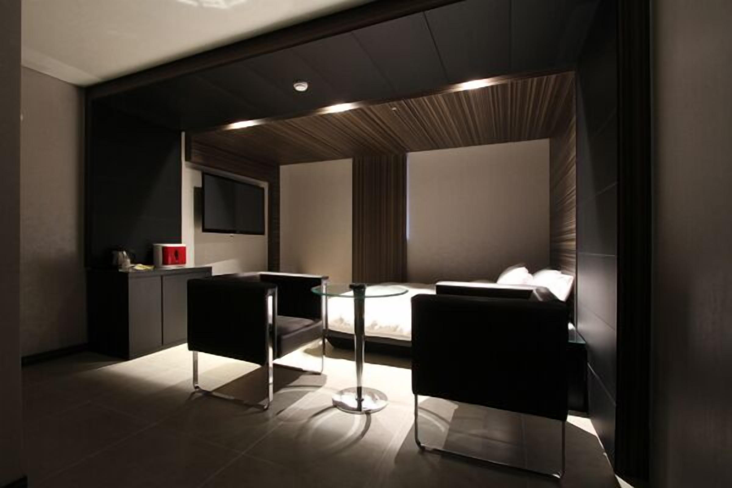 A modern hotel room with a bed, a small desk, and two chairs.
