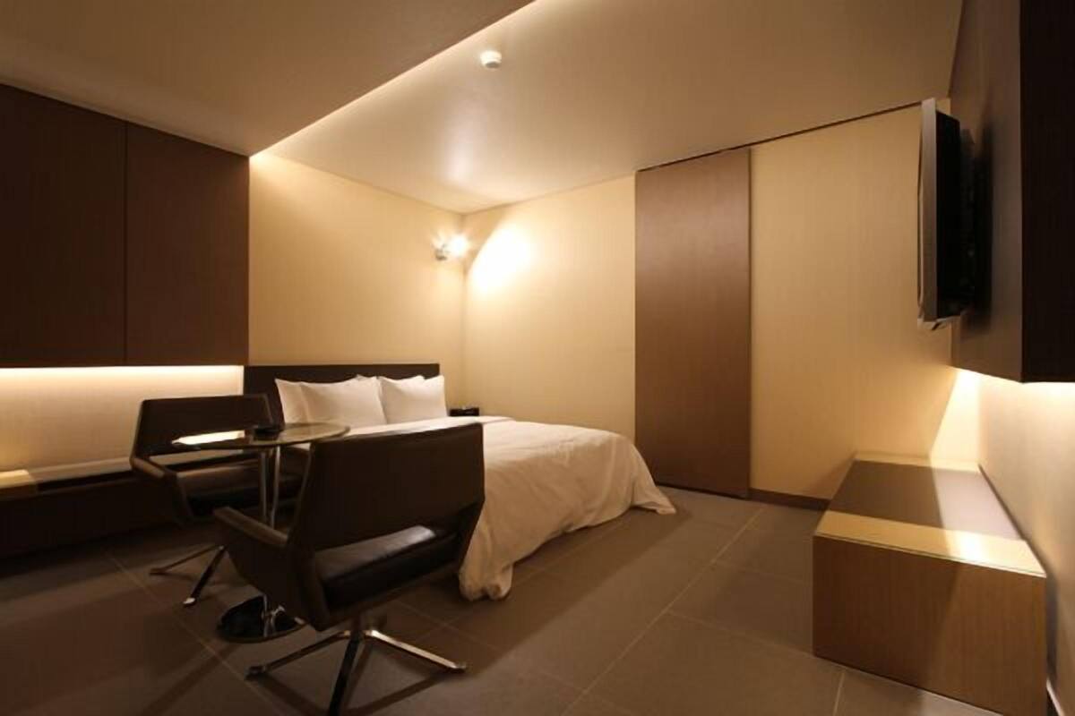 A modern hotel room with a bed, a desk, and a chair.