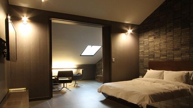 A modern bedroom with a large bed, a desk, and a skylight. - Valentine Hotel (Goyang)