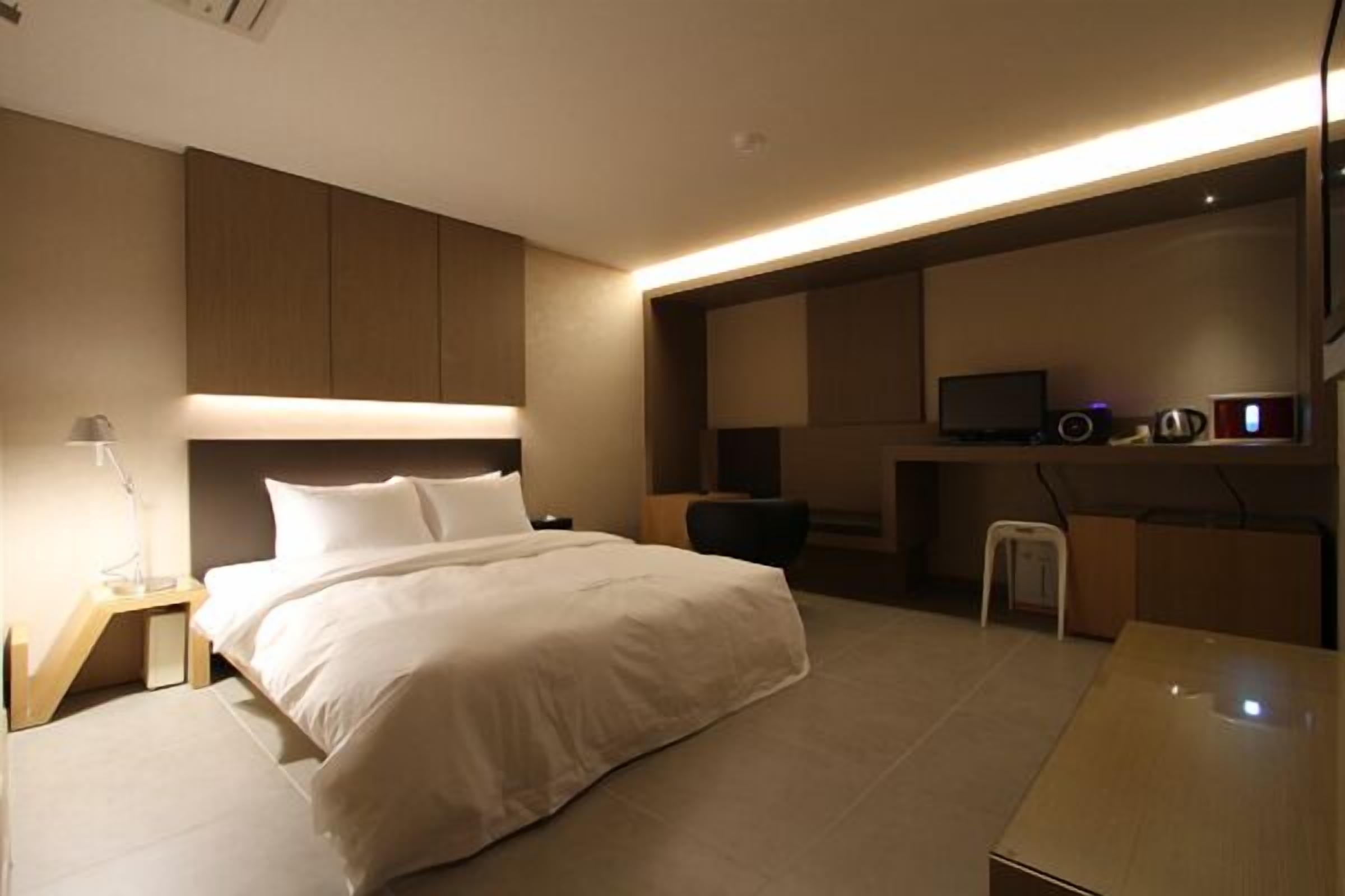 Een moderne hotelkamer met een groot bed, nachtkastjes, een bureau en een televisie.