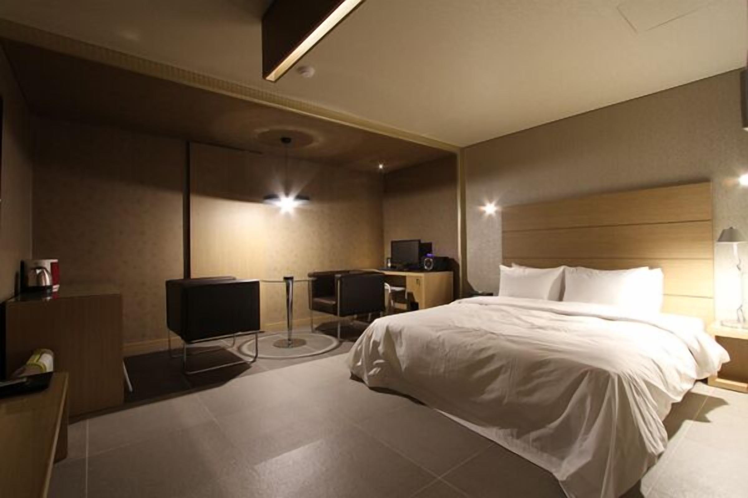 A modern hotel room with a large bed, a desk with a computer, and a television.