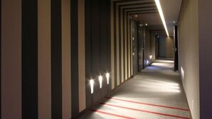 A modern hotel corridor with a geometric design, recessed lighting, and a carpeted floor. - Valentine Hotel (Goyang)