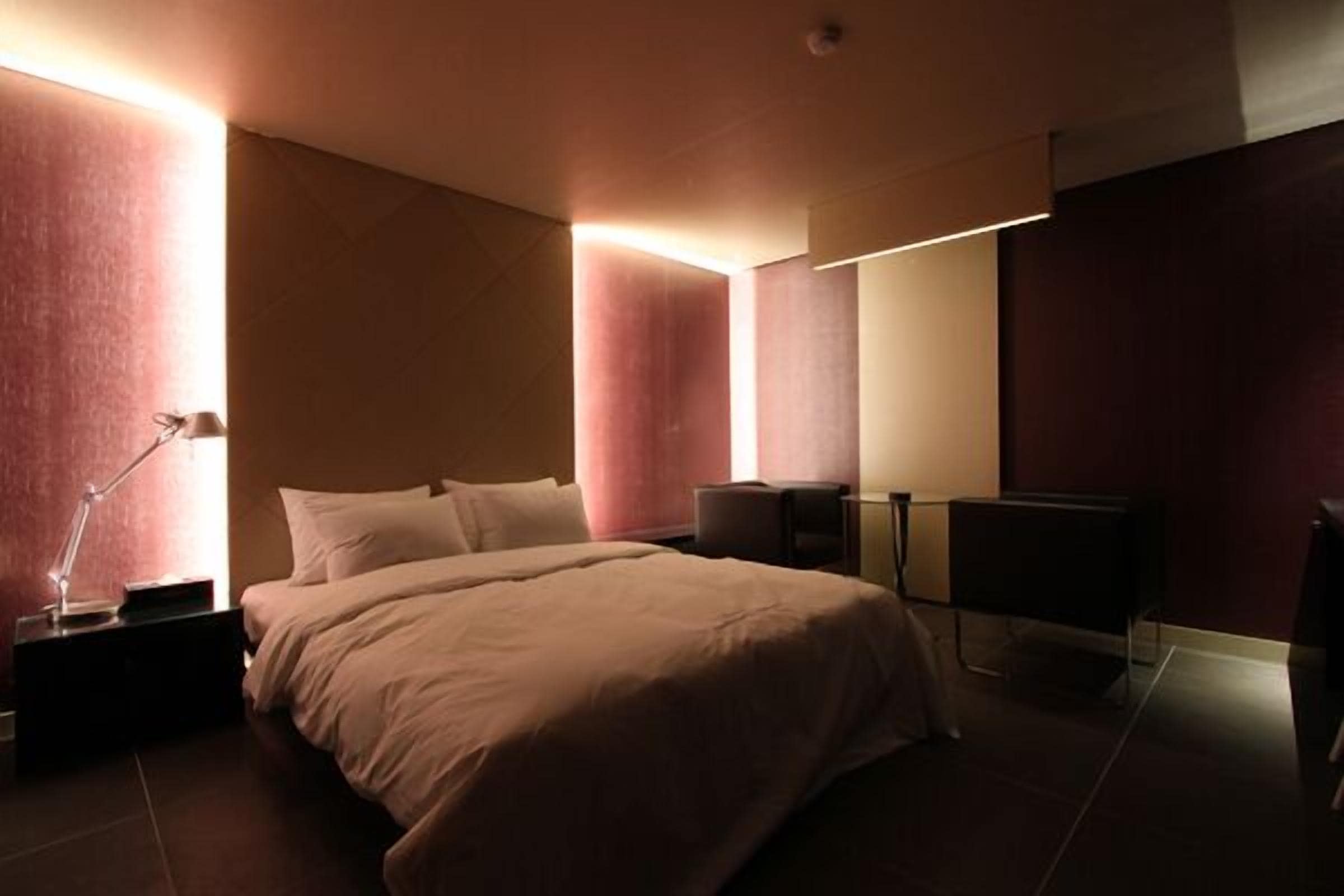 A modern bedroom with a large bed, bedside tables, a desk, and a chair.