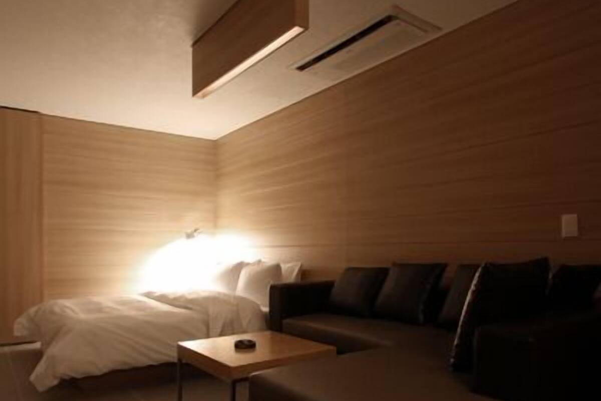 A modern hotel room with a bed, a sofa, and a small table.