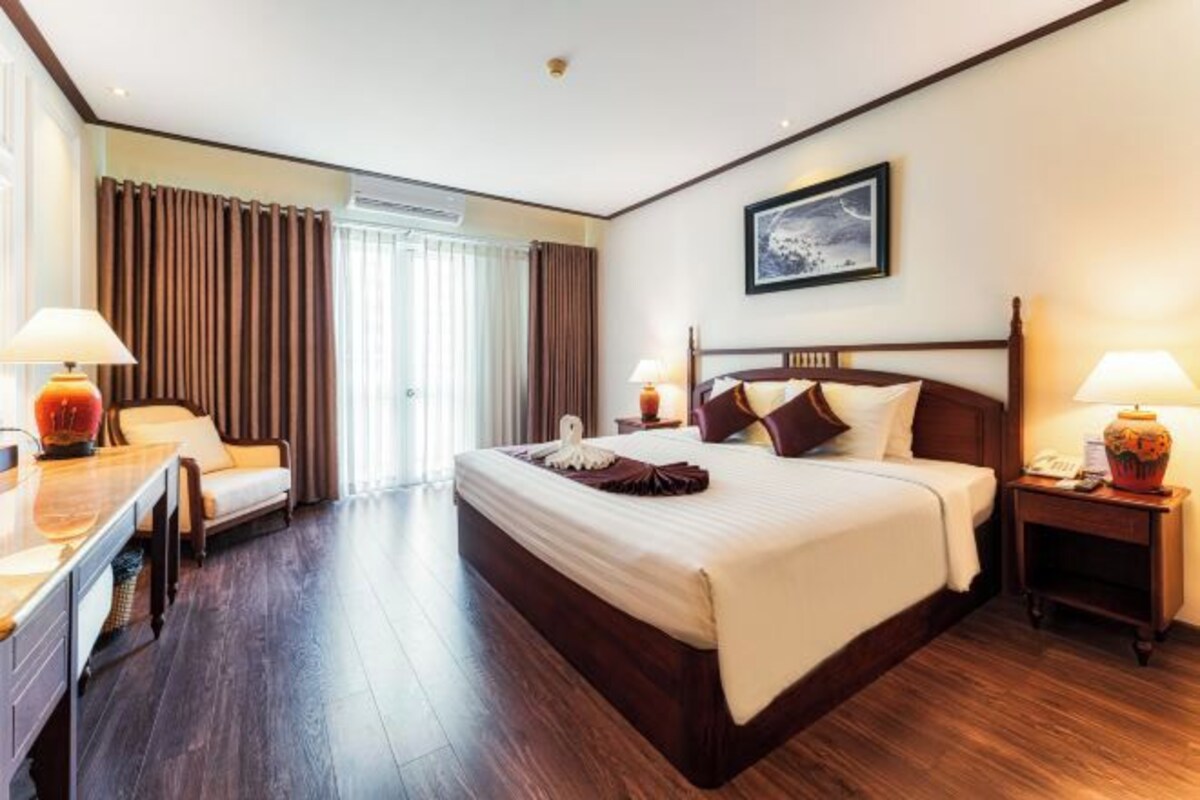 Een hotelkamer met een groot bed, nachtkastjes, een bureau en een stoel.