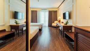 Une chambre d’hôtel avec deux lits, un bureau, une chaise, une télévision et une fenêtre avec des rideaux.