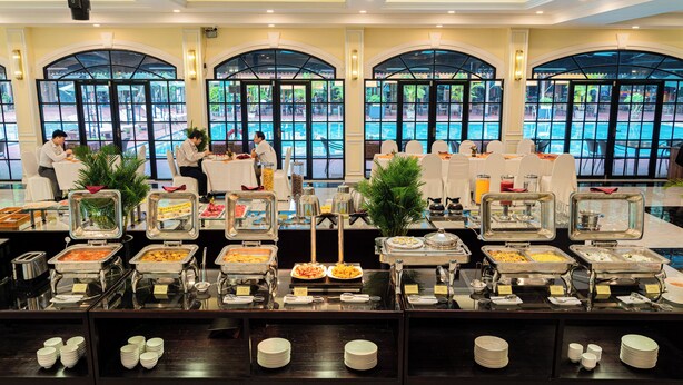 Un buffet avec plusieurs présentoirs de nourriture, des tables et des espaces aménagés pour s’asseoir.