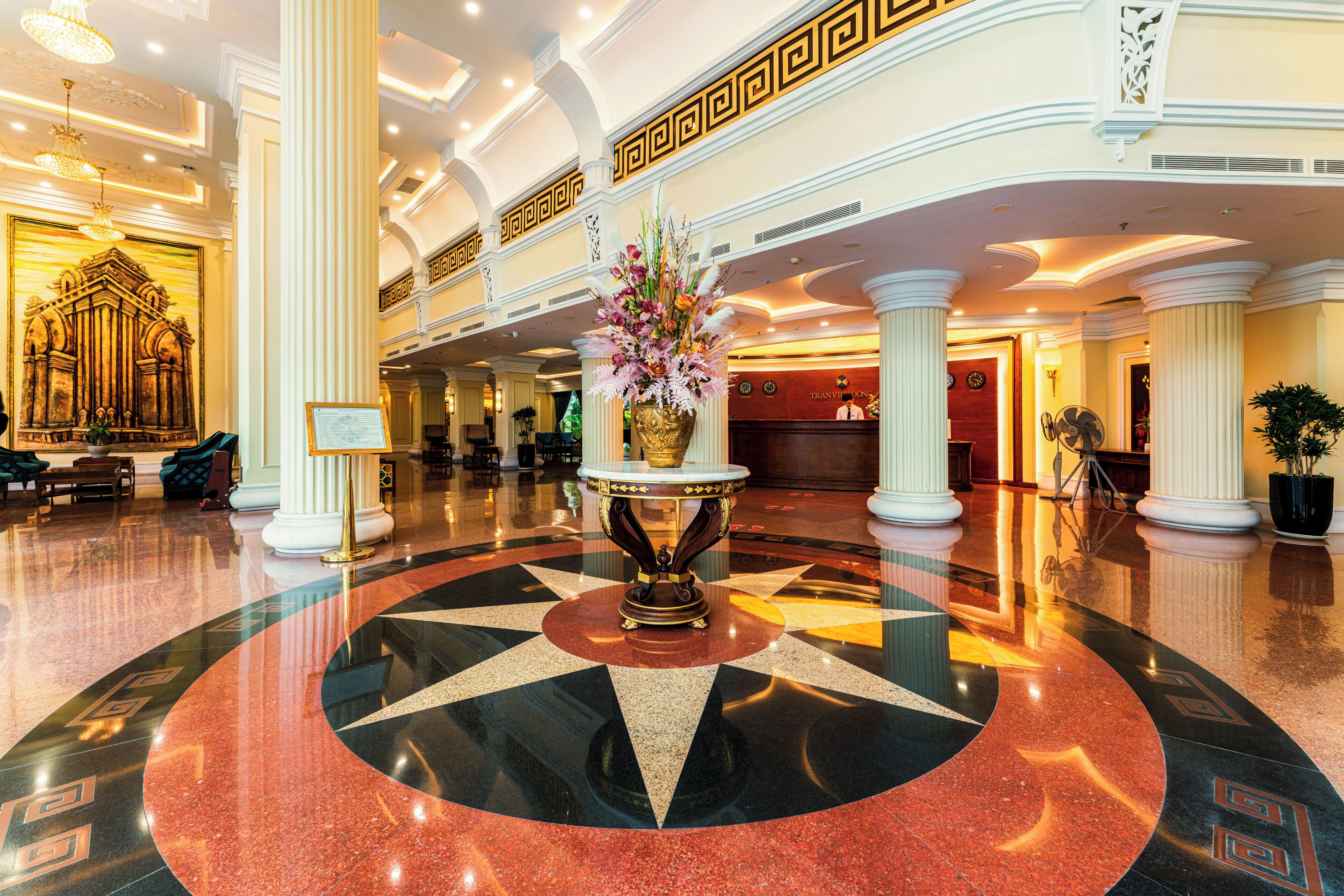A lobby with a star-shaped floor design, a central floral arrangement, and a reception desk.