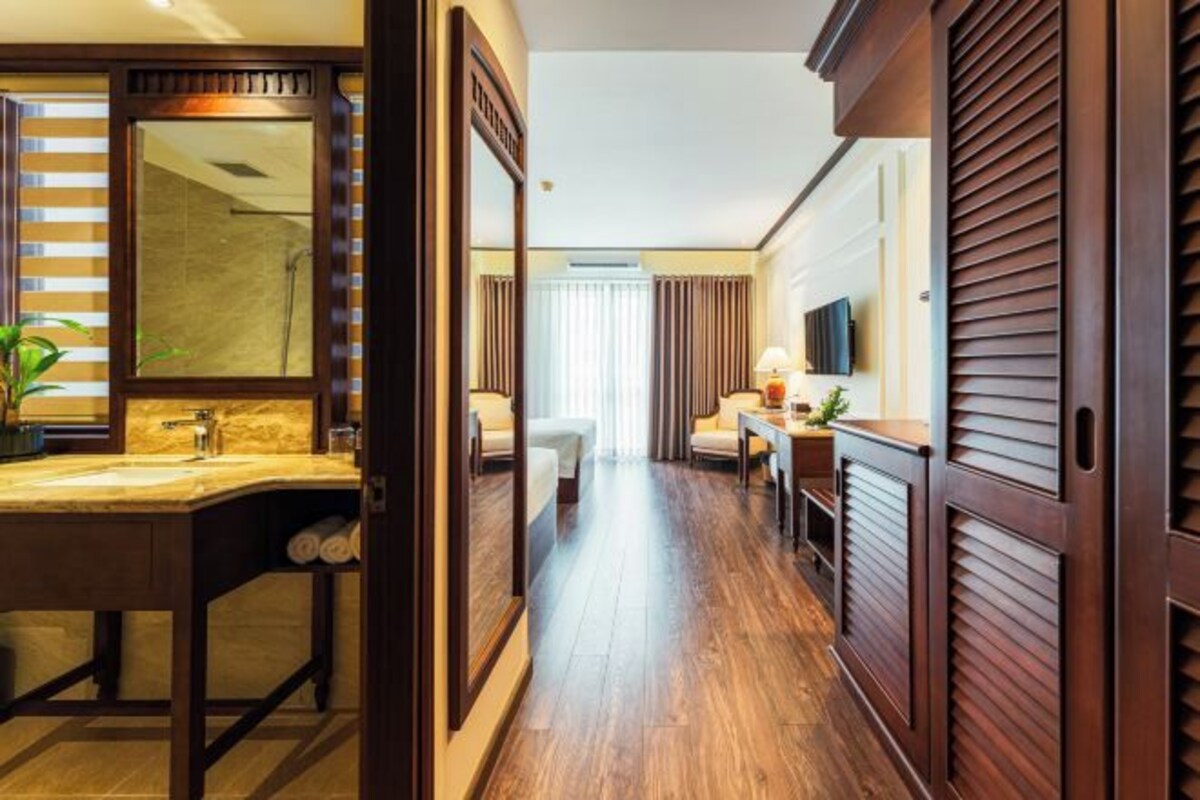 Une salle de bain d’hôtel avec un grand miroir, un lavabo et un espace douche.