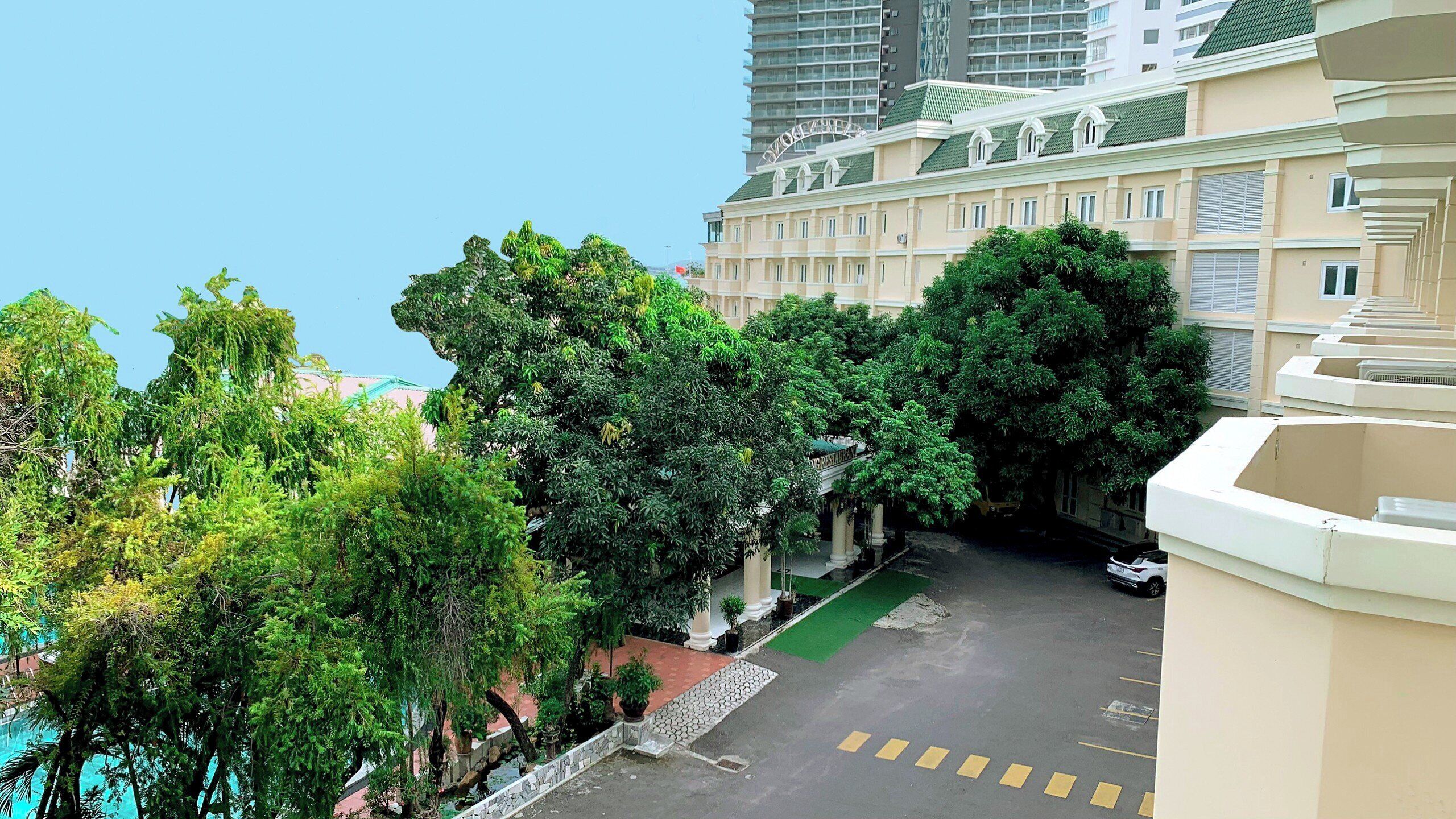A residential area with a green lawn, a paved road, and a building with a green roof.