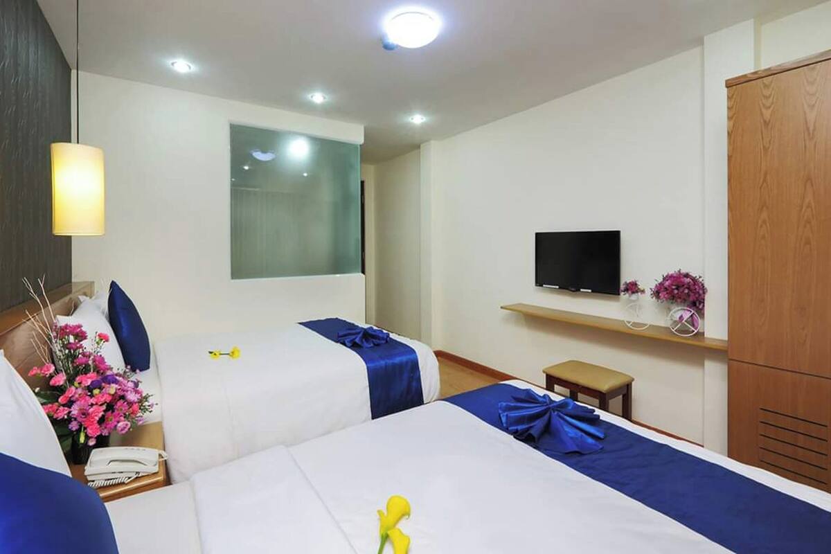 A hotel room with two beds, a TV, a small table, and a wardrobe.