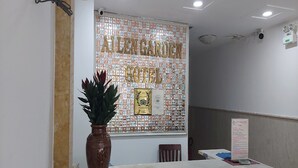 A reception area with a wall decorated with currency notes, a potted plant, and a signboard. - Ailen Hotel (Ho Chi Minh City)