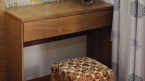 A wooden vanity with a mirror, a vase of flowers, and a patterned stool. - Ailen Hotel (Ho Chi Minh City)