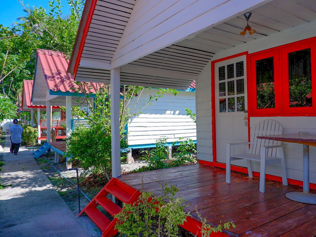 A covered porch with a red and white color scheme, a white chair, and a table.