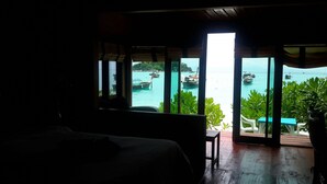 Une chambre avec un lit, une table et une vue sur les bateaux qui naviguent, grâce à de grandes fenêtres.