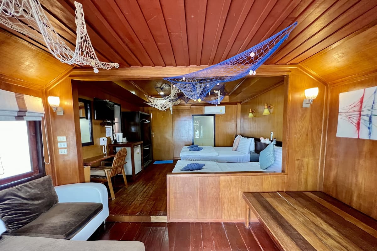 Una cabaña acogedora con paredes y suelos de madera, una pequeña kitchenette, una cama con almohadas y una hamaca.