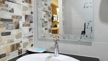 A bathroom with a white sink, a mirror with decorative frame, and a mosaic tile wall.