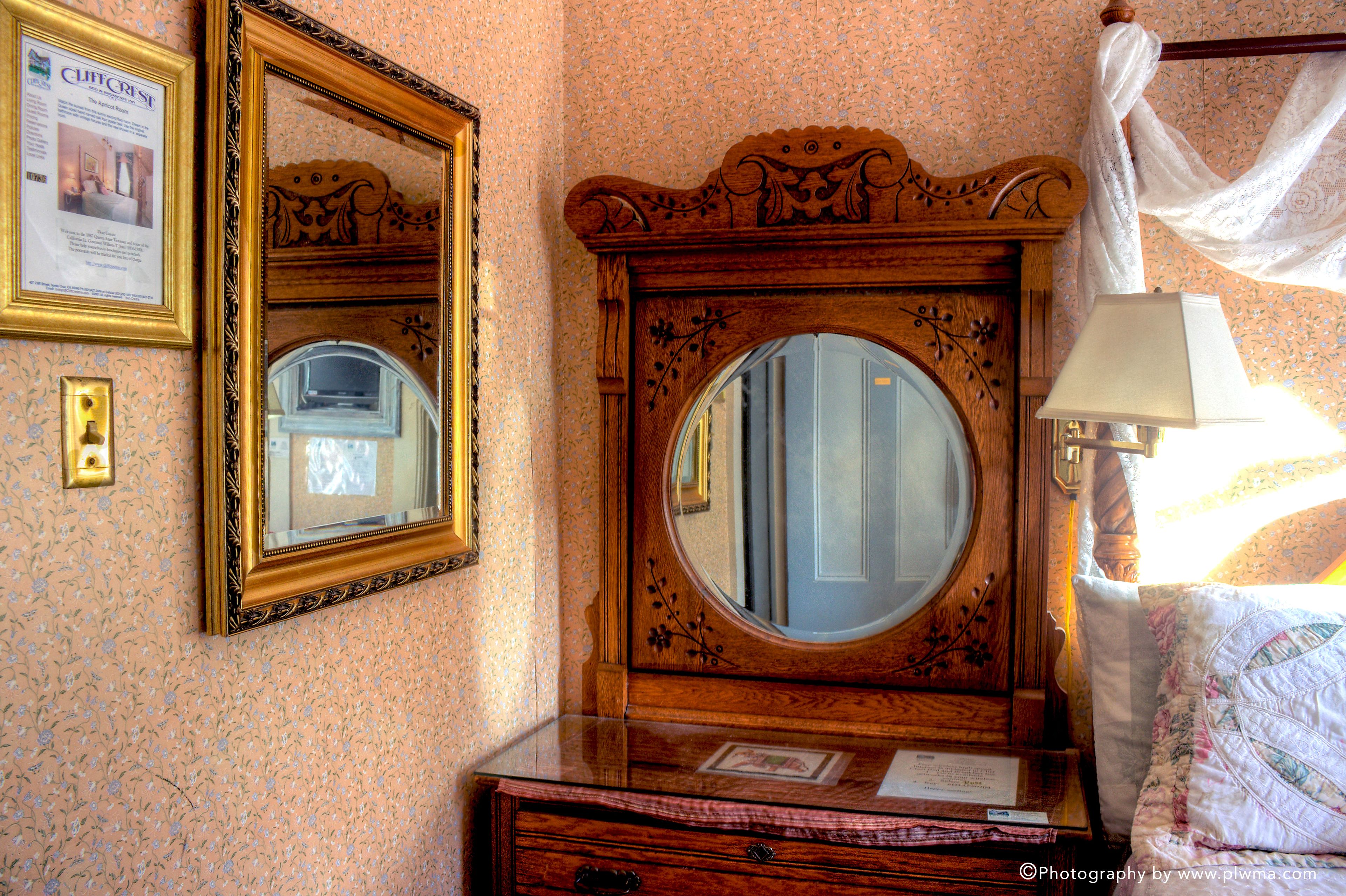 A wooden dresser with a mirror, a framed picture, and a lamp.
