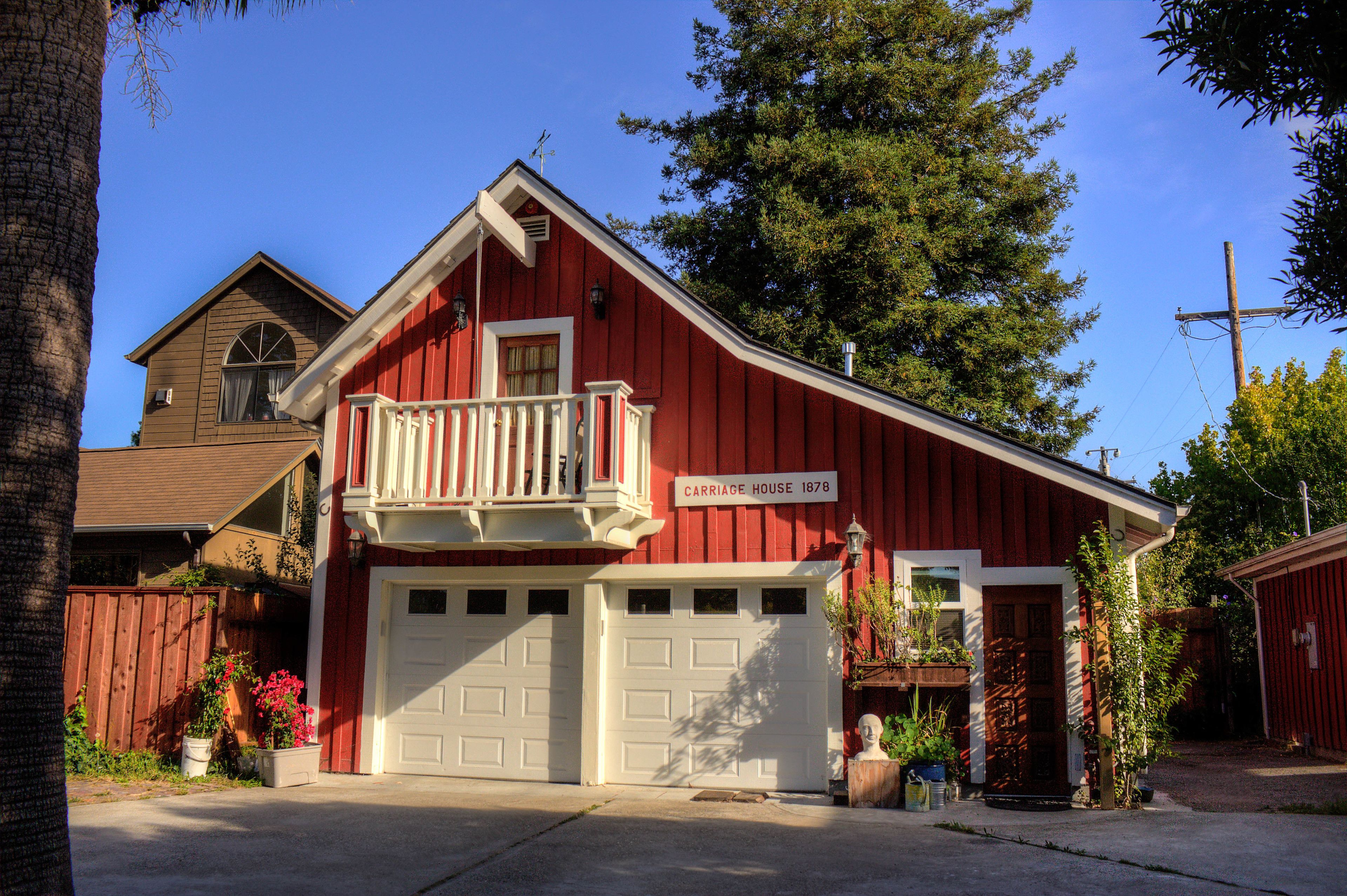 A red barn-style house with a balcony, a garage, and a sign reading "Carriage House 1878".