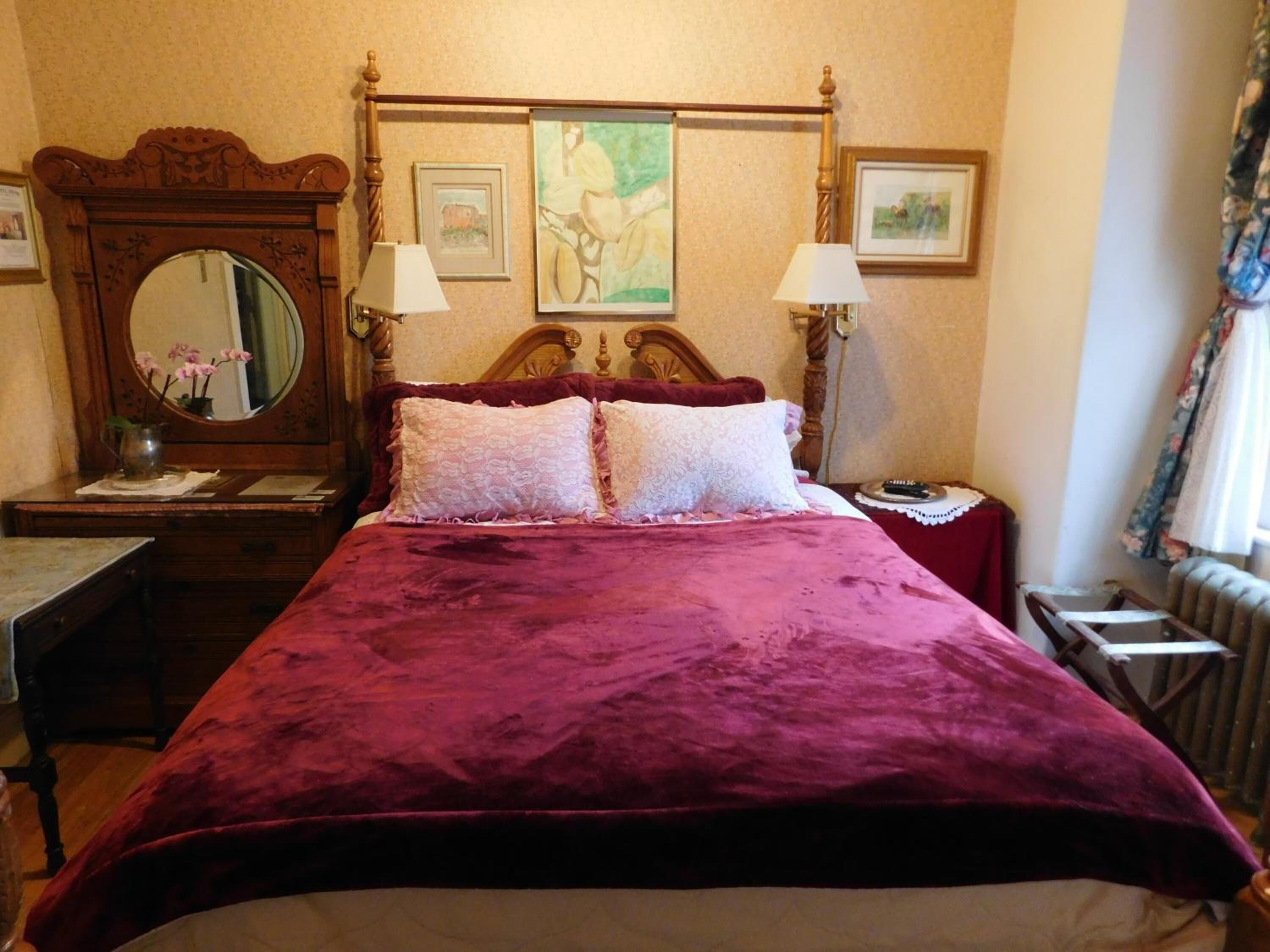 Une chambre avec un grand lit, deux tables de chevet, une tête de lit en bois et un miroir.