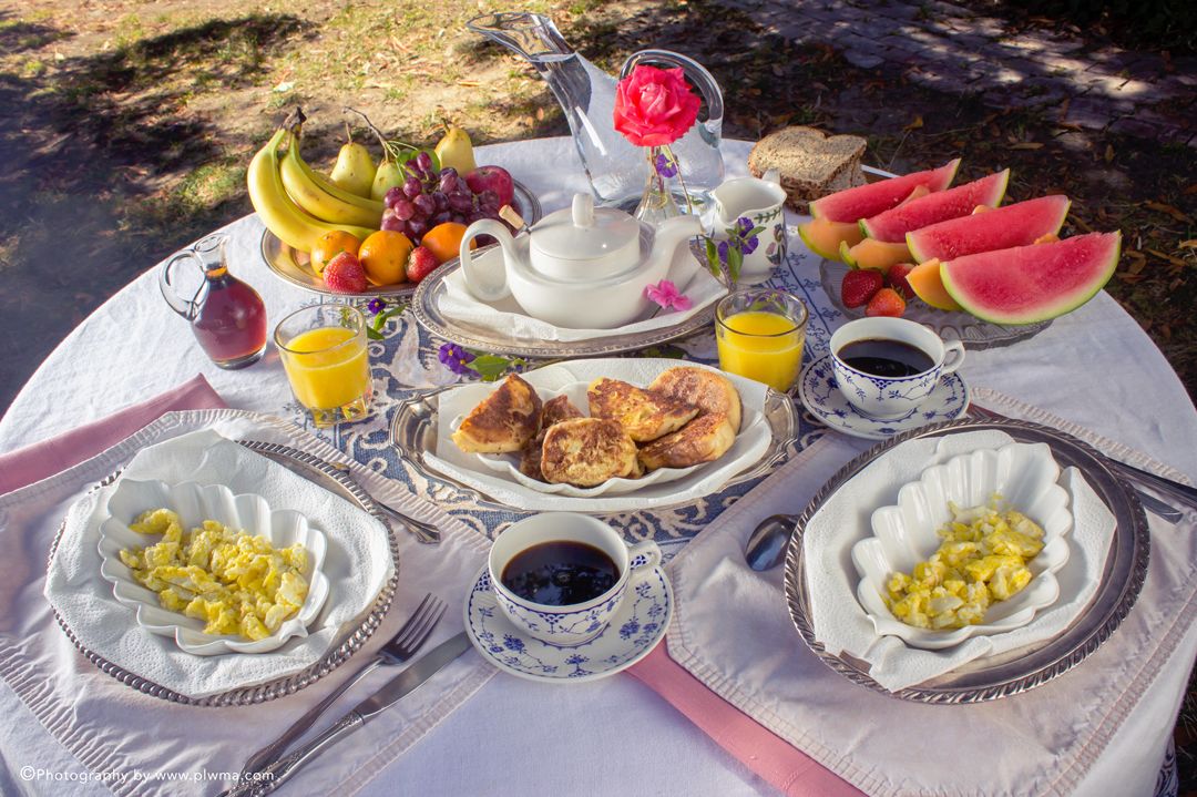 A picnic setup with a variety of foods and drinks on a table outdoors.
